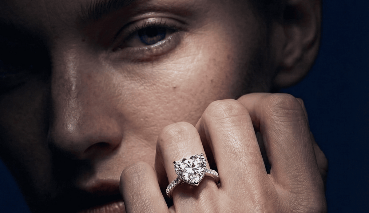 Close-up of a person wearing a diamond ring on a dark background