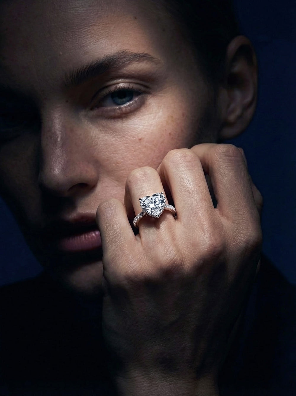 Close-up of a woman wearing a diamond ring with a dark background