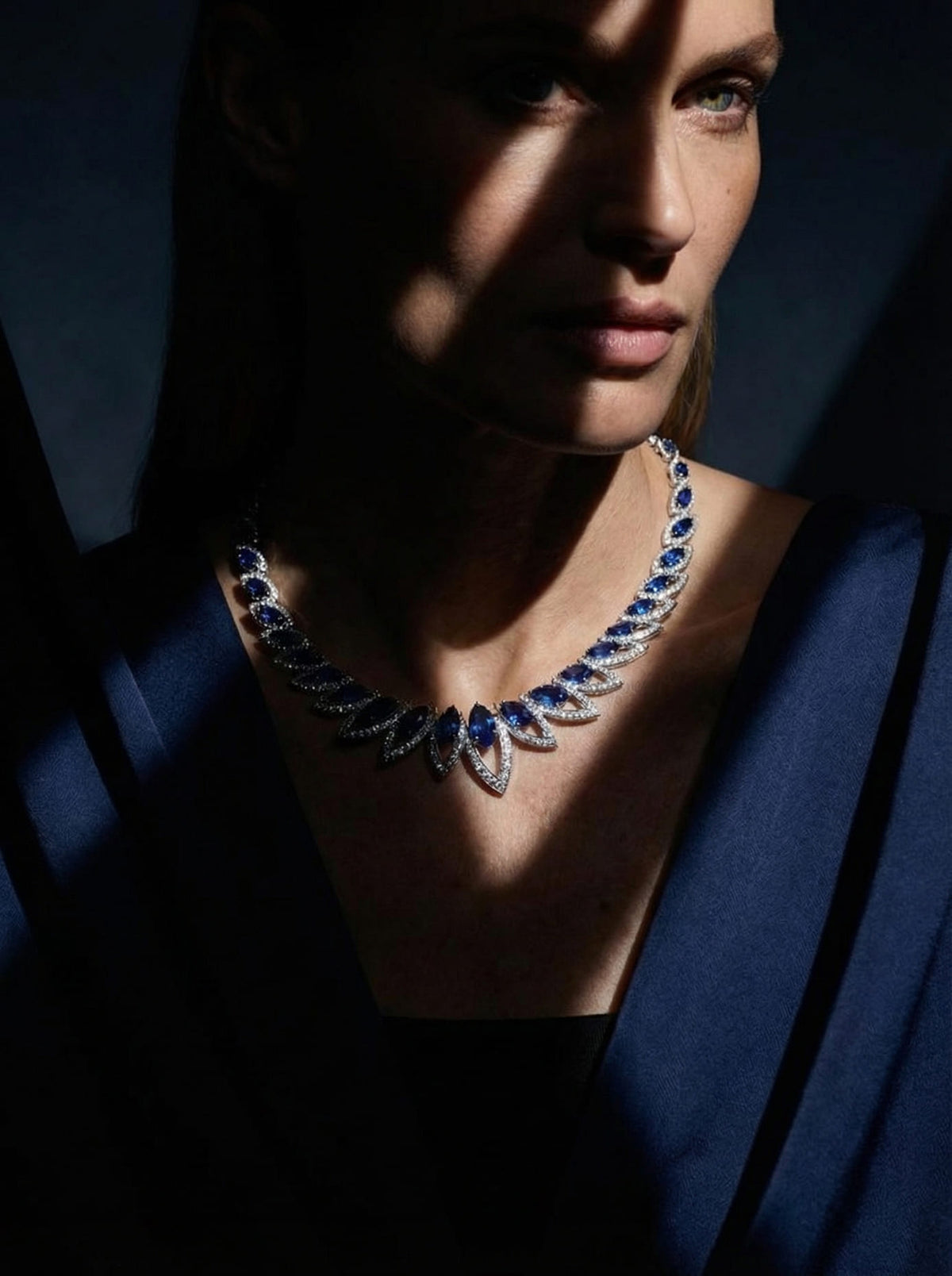 Woman wearing a luxurious blue and white gold necklace against a dark background