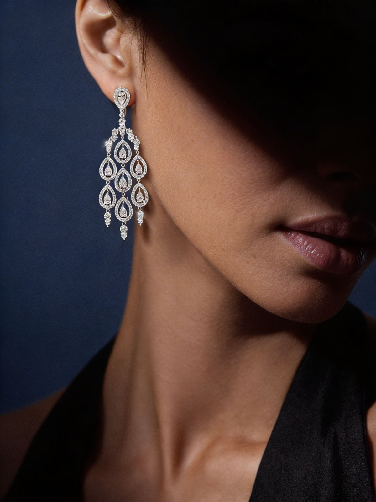 Close-up of a woman wearing a diamond earring against a dark background